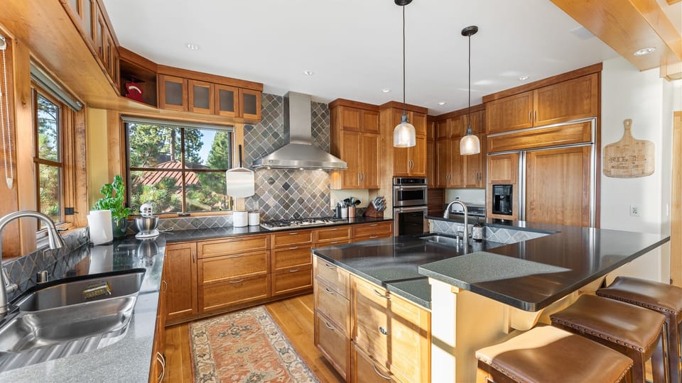 The heart of the home is a fully stocked chef's kitchen, complete with high-end appliances, ample counter space, and a large island with seating for five. Whether you're preparing a casual meal or hosting a holiday dinner, this kitchen is a cook's dream.