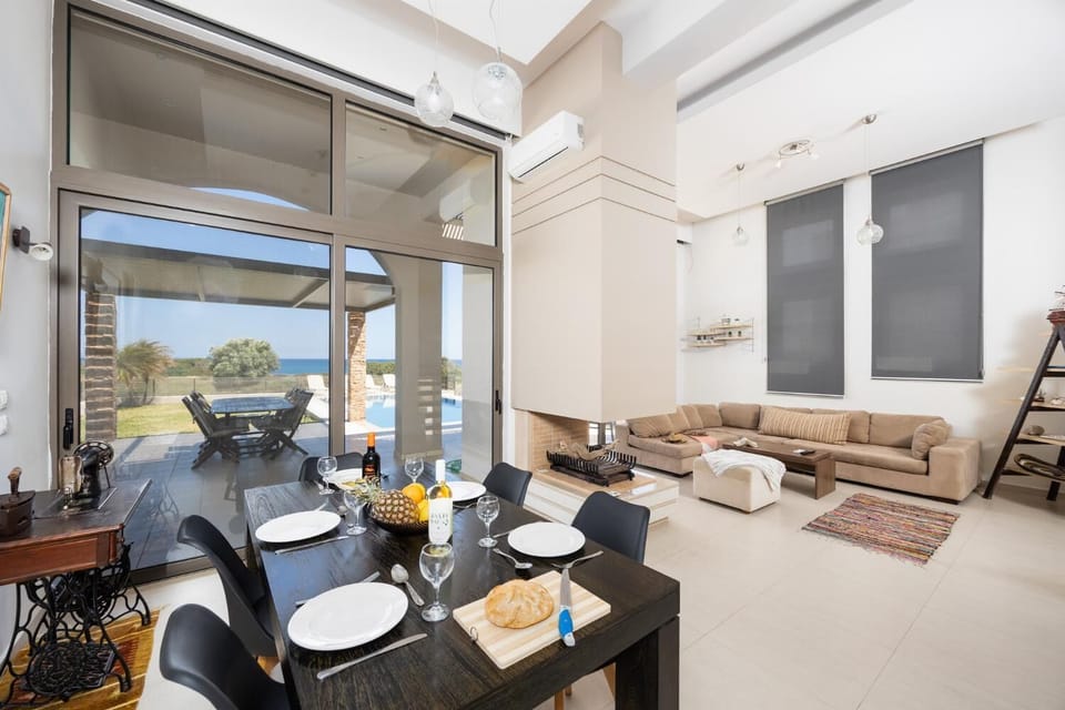Open-plan living room with sofas, dining area, kitchen, ornamental fireplace, A/C, WiFi internet, satellite TV, and sea views
