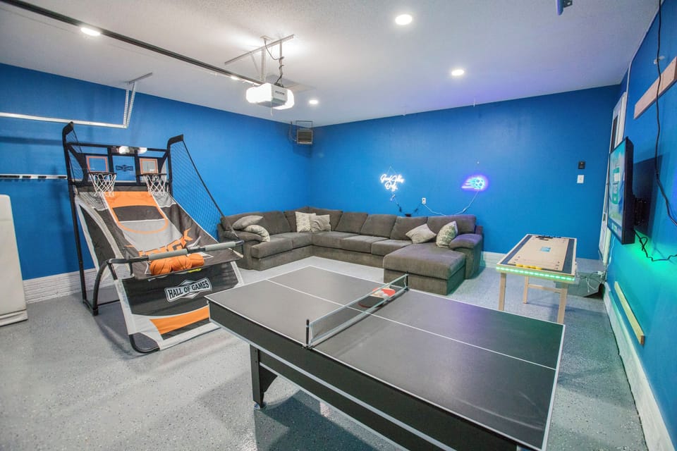 Game room with TV, shuffleboard, dual basketball, pool table/ping pong table combo and dart board.