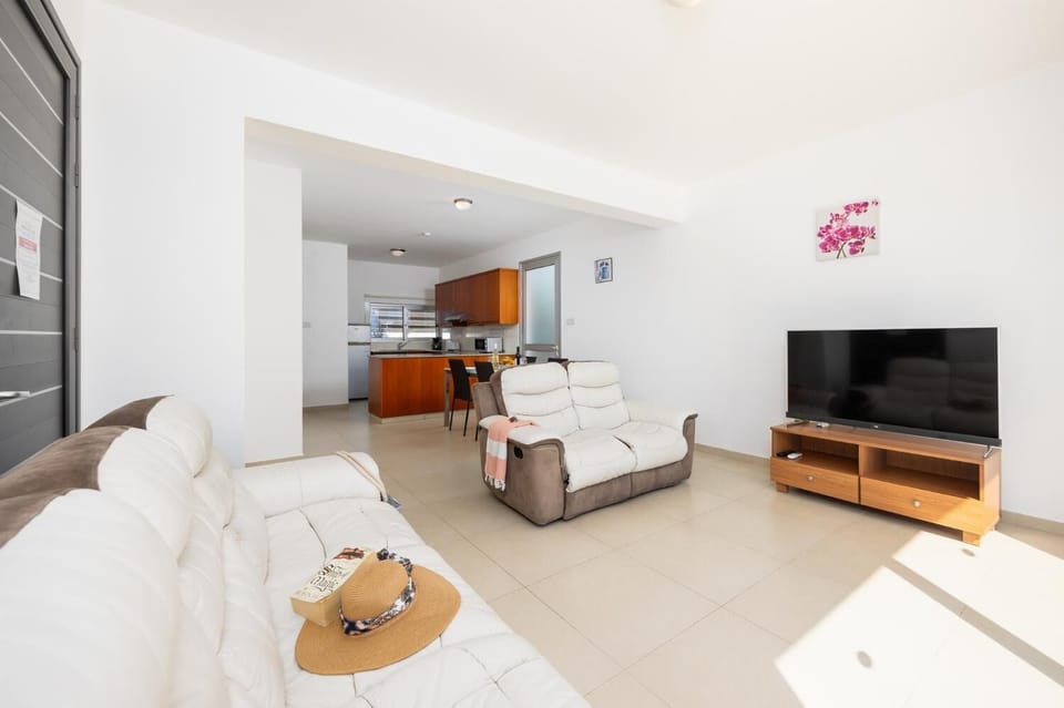 Open-plan living room with sofas, dining area, kitchen, A/C, WiFi internet, and satellite TV
