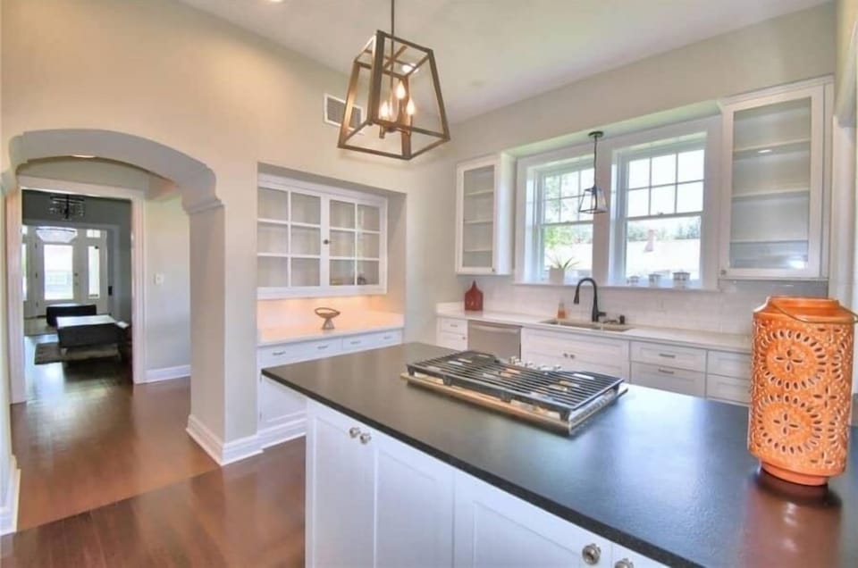 Kitchen island with gas cooktop. View through butlers pantry arch to front door