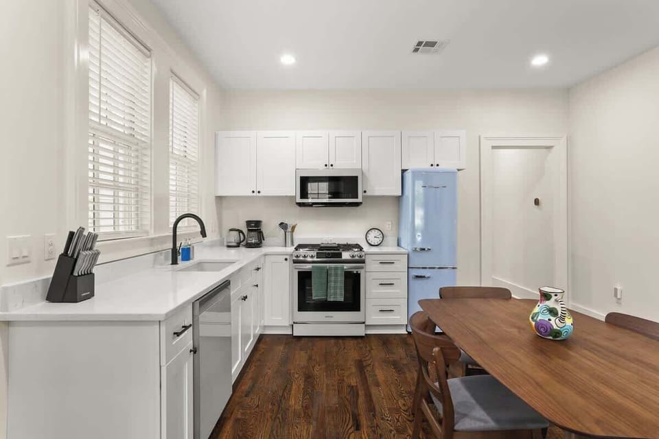 Fully equipped kitchen with modern appliances, quartz counters, and retro-style fridge, plus dining table for shared meals.