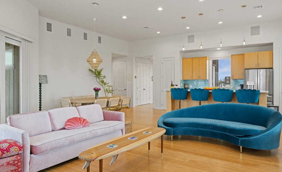 Unit 2118 — Dining area with teak table, cane-back chairs, roses, rattan pendant, and ocean-view sliding doors