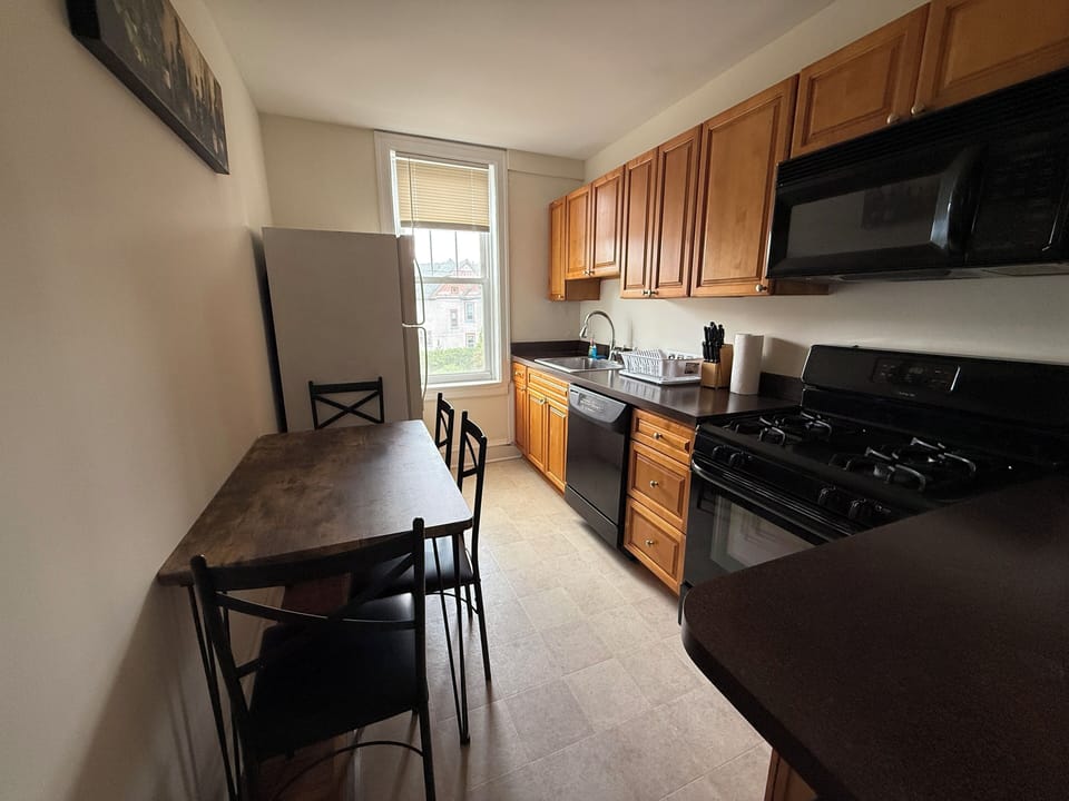 Step into a thoughtfully designed kitchen, featuring a full-sized refrigerator, range, and plenty of prep space, along with a dining table. The generous cabinetry ensures ample storage, making organization a breeze.
