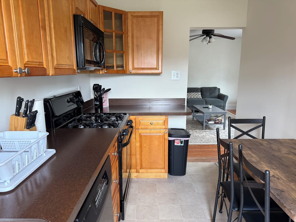 Step into a thoughtfully designed kitchen, featuring a full-sized refrigerator, range, and plenty of prep space, along with a dining table. The generous cabinetry ensures ample storage, making organization a breeze.
