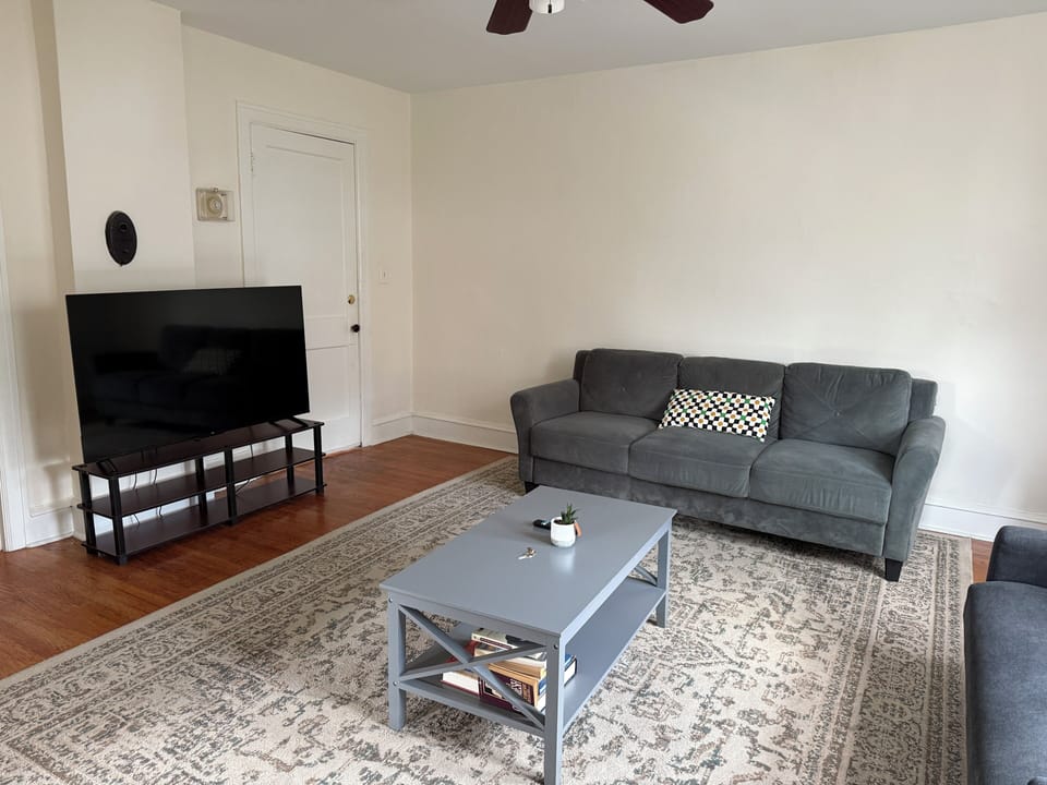 The living room is furnished with all the essentials, including a cozy sofa, coffee table, and TV, offering immediate comfort and a welcoming atmosphere from the moment you move in.