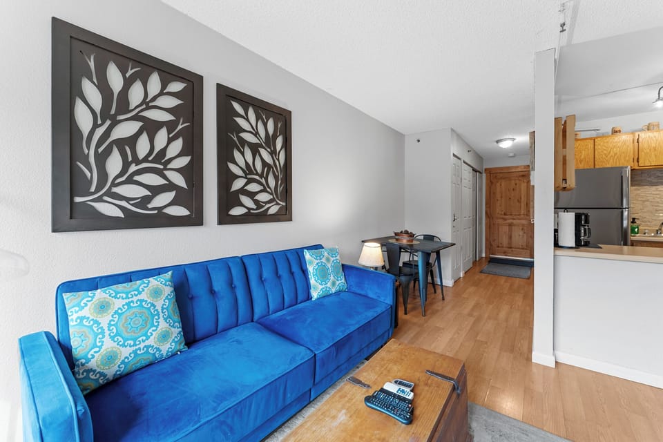 Sink into your plush blue sofa after exploring the city, with stylish botanical art creating a calming backdrop for your stay.