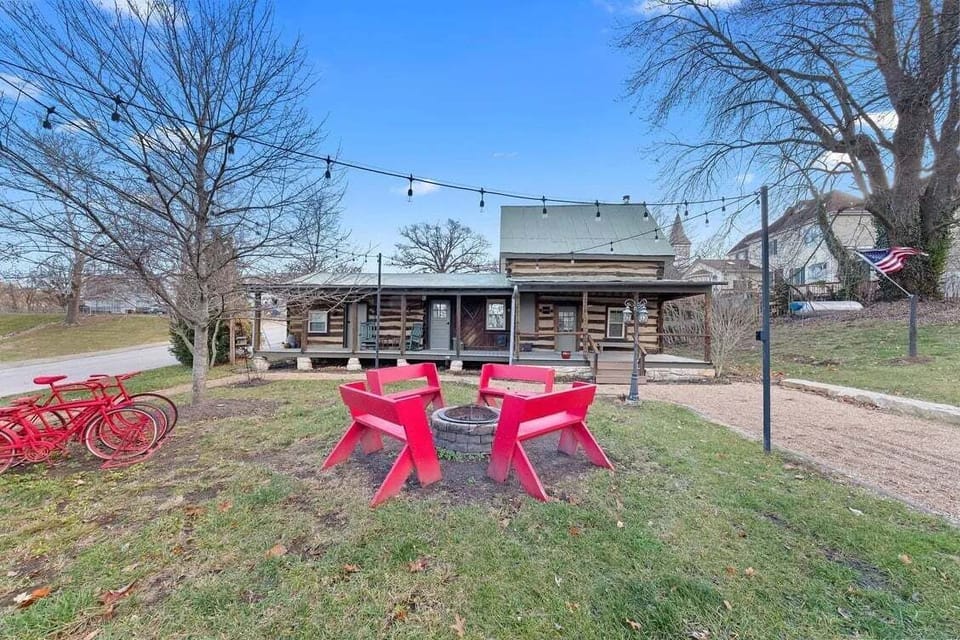The landscaped cabin grounds include outdoor Adirondack seating, string lights, gravel paths, mature trees, and red cruiser bicycles.