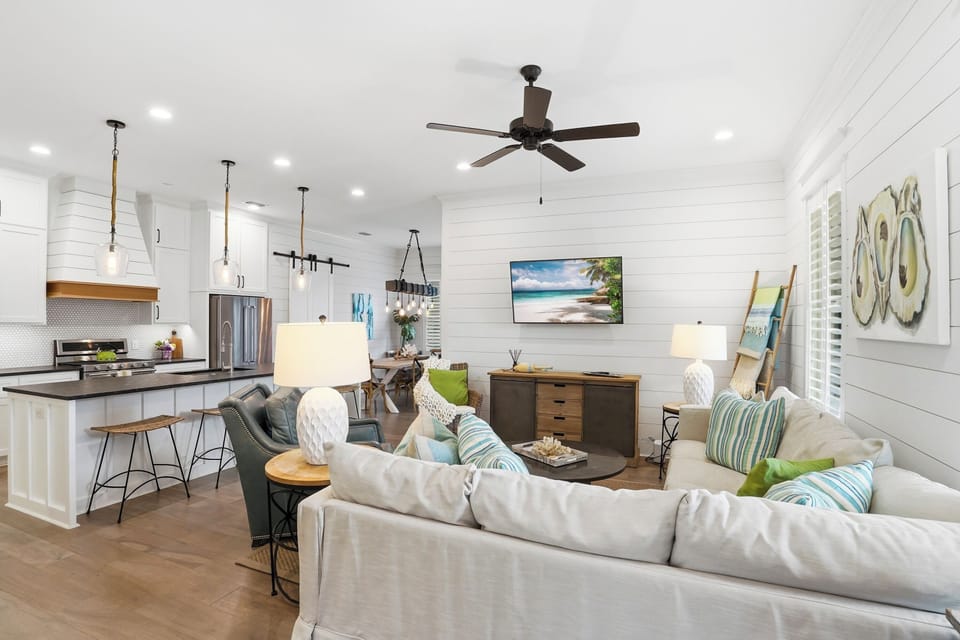 Open Living Room, Kitchen, And Dining Area - The main floor connects sectional seating, island stools, a gas range, and the dining table so the group can stay together.