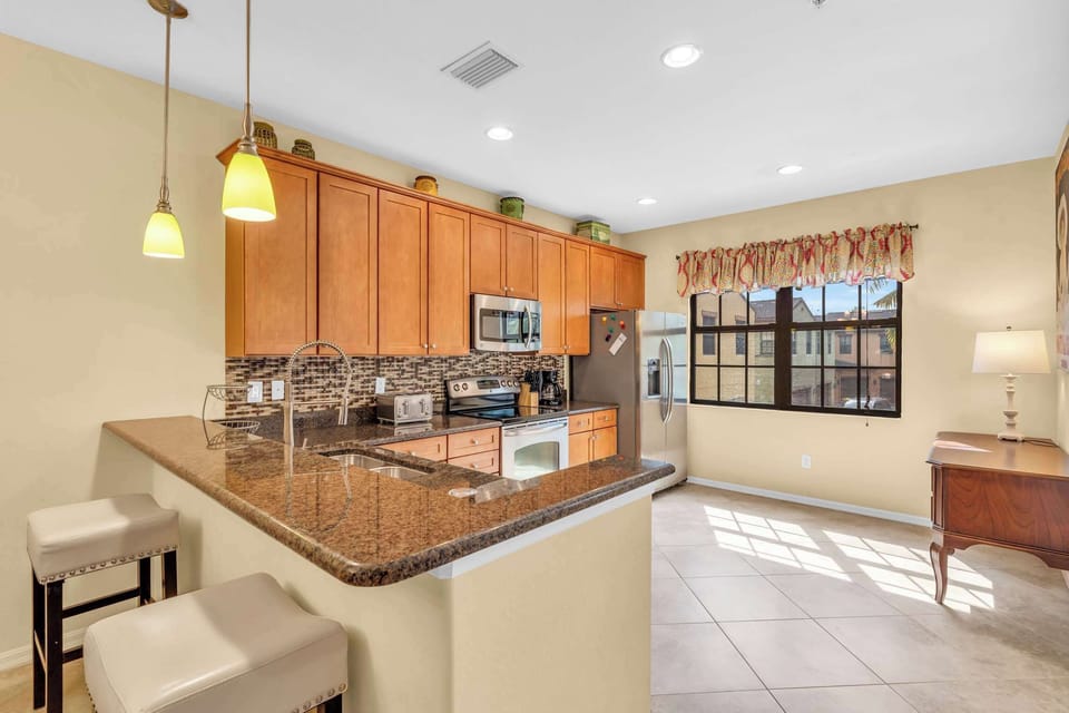 There are 2 bar stools at the kitchen counter and the kitchen has a large window looking out towards the quad 