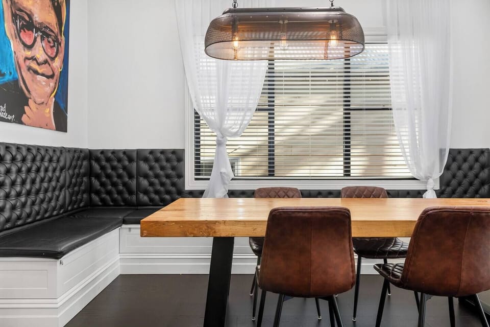 The feature dining table is surrounded by cushioned banquette seating and boasts unique pendant lighting, adding a touch of elegance to the space. 


