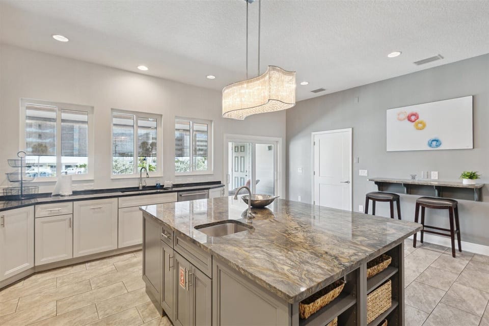 A spacious, upscale kitchen featuring a large marble island with an undermount sink and ample counter space.