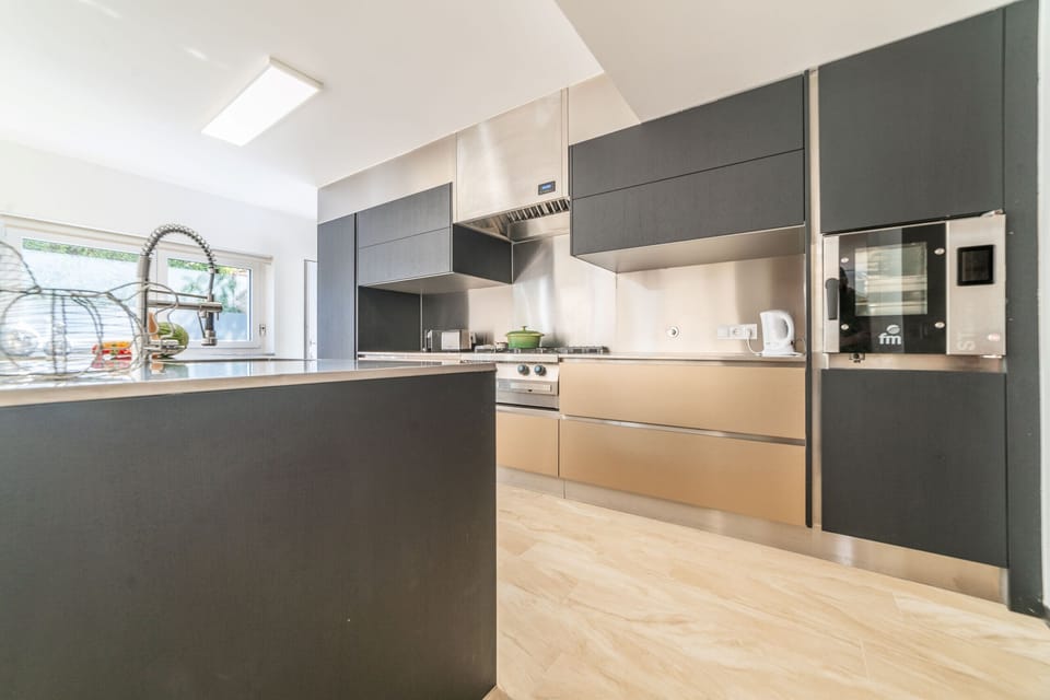 Modern open-plan kitchen with grey and wood cabinetry — Villa Geranios, luxury holiday villa in Belverde