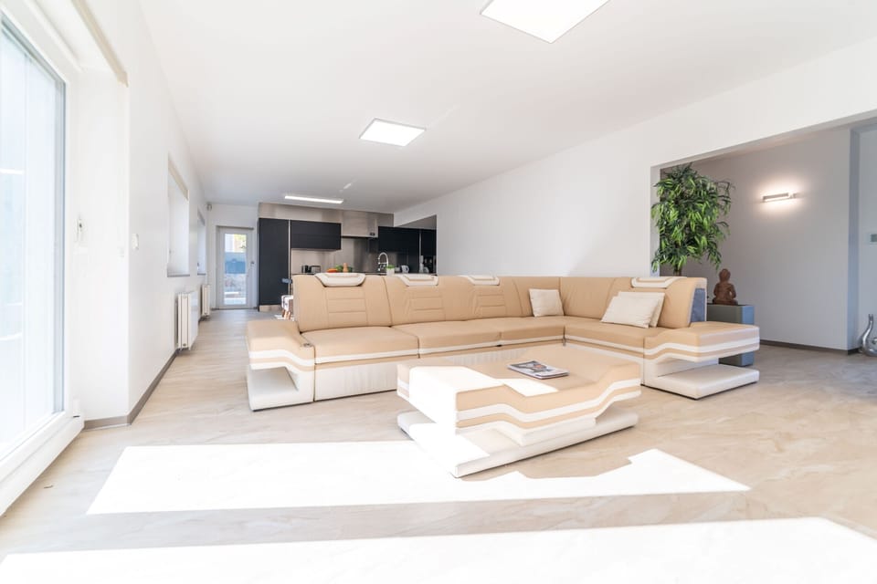 Bright open-plan living room with cream leather corner sofa — Villa Geranios, luxury holiday villa in Belverde