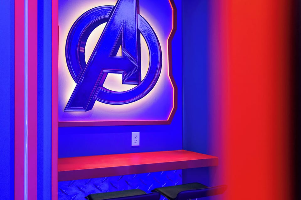 Discover a lively space dedicated to your favorite superheroes, with a striking red and blue design. The glowing Avengers logo adds a fun vibe, and black stools by a bright countertop are ideal for snacks or games.