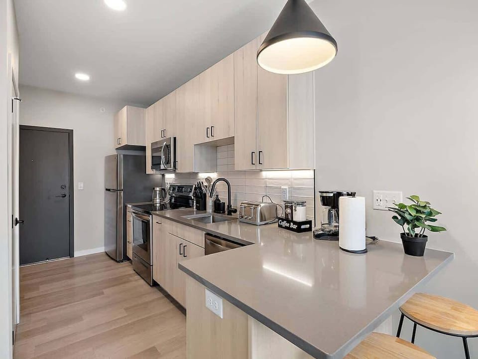 Chic kitchen with breakfast bar, stainless steel appliances, and stylish lighting!