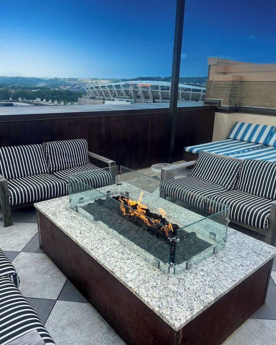 Rooftop retreat with cozy firepit, striped seating, and stunning stadium views.