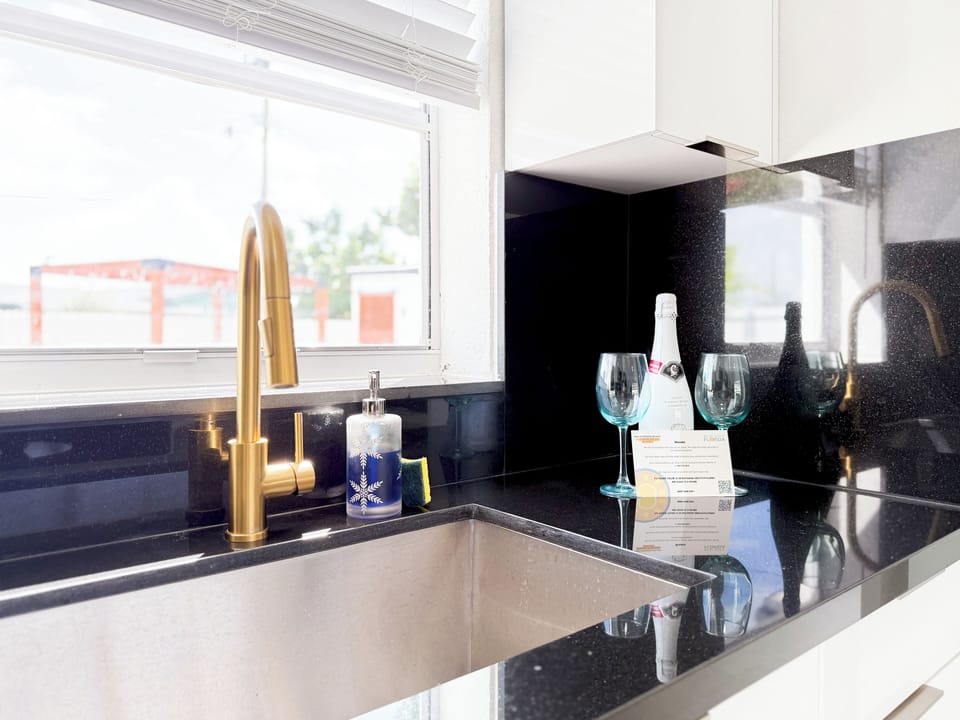 Elegant kitchen with gold fixtures & black counters.