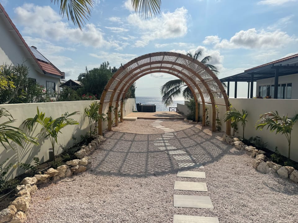 Arch over garden leading to patio, stairs and jacuzzi