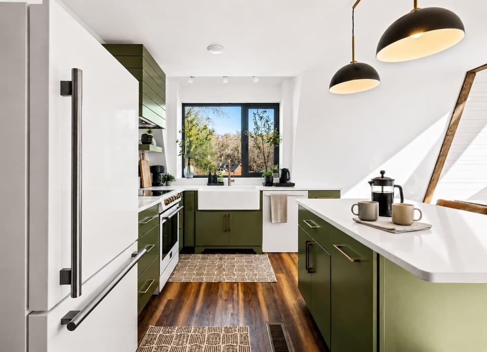 

Designer chef's kitchen with forest green custom cabinetry, luxury stone countertops, stainless steel appliances, luxury vinyl plank floors, and natural light — fully stocked for gourmet cooking in the Smoky Mountains.