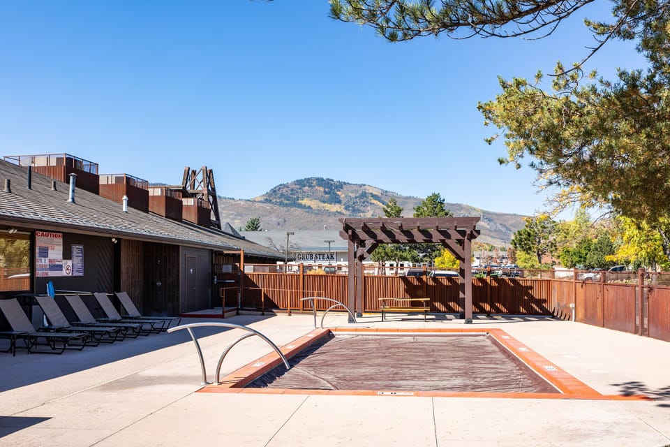 Outdoor hot tub area with plenty of lounge chairs and mountain views in the distance.