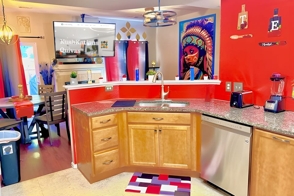 The vibrant red kitchen, with warm wood tones, offers an inviting atmosphere enhanced by a large flat-screen TV & a captivating Native American painting. This functional kitchen is perfect for