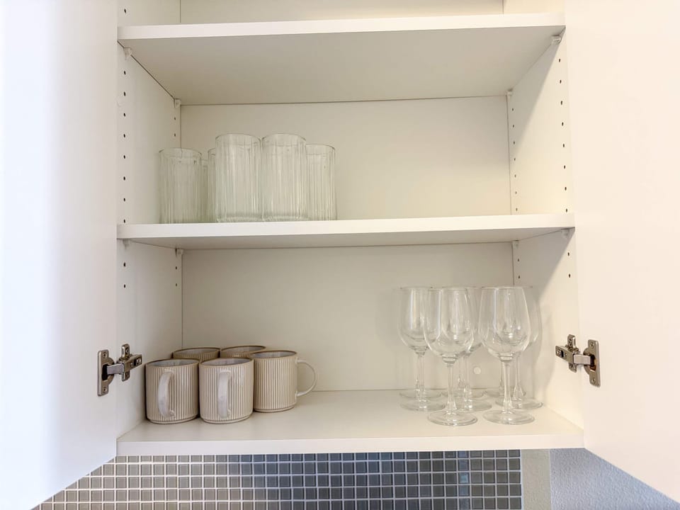 Fully equipped kitchen shelf with tea cups and wine glasses