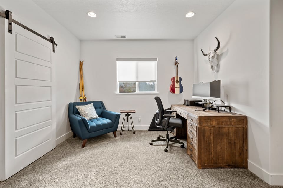 Bright and inviting office space featuring a sleek desk, comfortable office chair, and a stylish blue Art Deco-inspired guest chair for added charm.