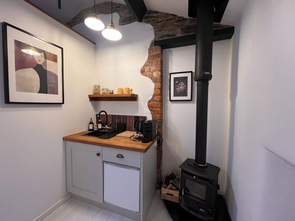 Kitchenette, beside wood-burning stove and exposed original brickwork details