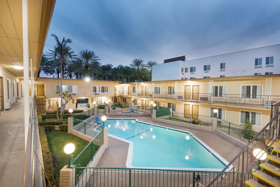 Linger poolside at dusk with soft lights and palm silhouettes.