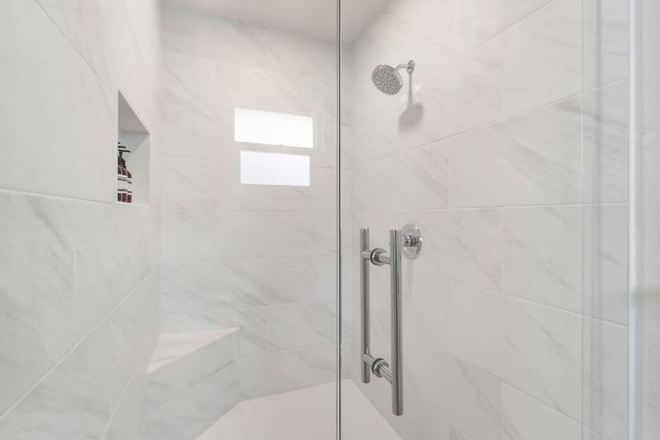 The glass enclosed shower in the main bathroom includes a built in seat 