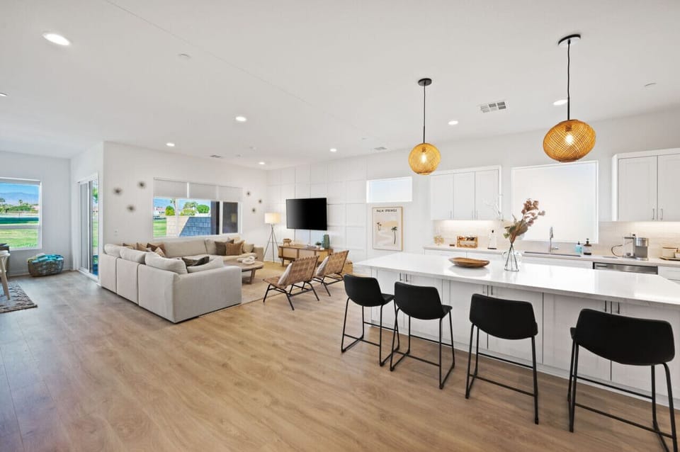 Spacious open layout blending kitchen, dining & living areas under warm pendant lighting.