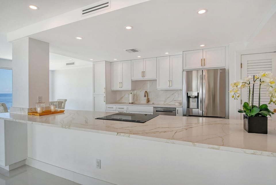 Marble countertop island with built-in cooktop separates the kitchen from the dining area.