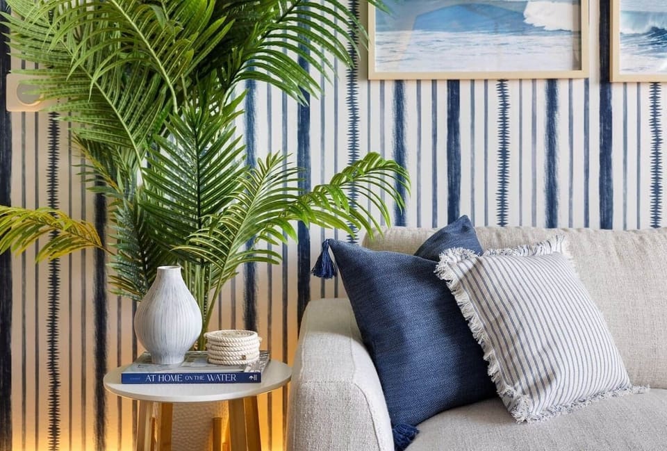 Take a seat on our cozy couch, accented with textured blue and striped pillows, adding a nautical charm to the coastal-inspired decor. Sip your morning coffee and dive into 'At Home on the Water' for the perfect relaxing retreat.