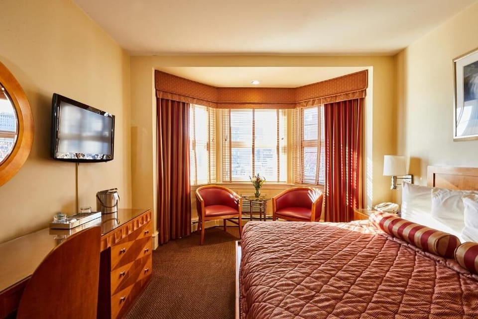 Settle into a sunlit bedroom with cozy seating and city vibes.