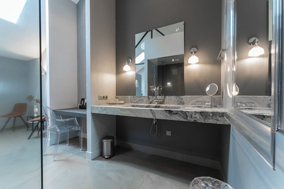 A luxurious bathroom vanity area featuring a large mirror and stylish marble countertop, complemented by elegant lighting and sleek fixtures, creating a sophisticated and functional space.
