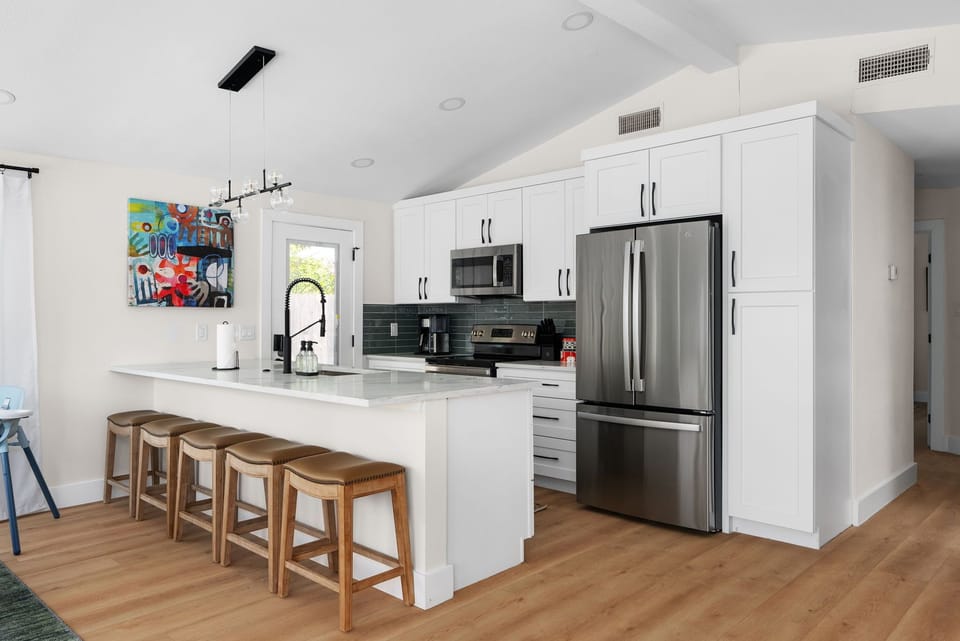Featuring a microwave, fridge, stove, and coffee maker. The sleek white cabinets add a touch of elegance to this inviting environment. Whether you're an experienced chef or just starting out, this kitchen has everything you need for cooking success!