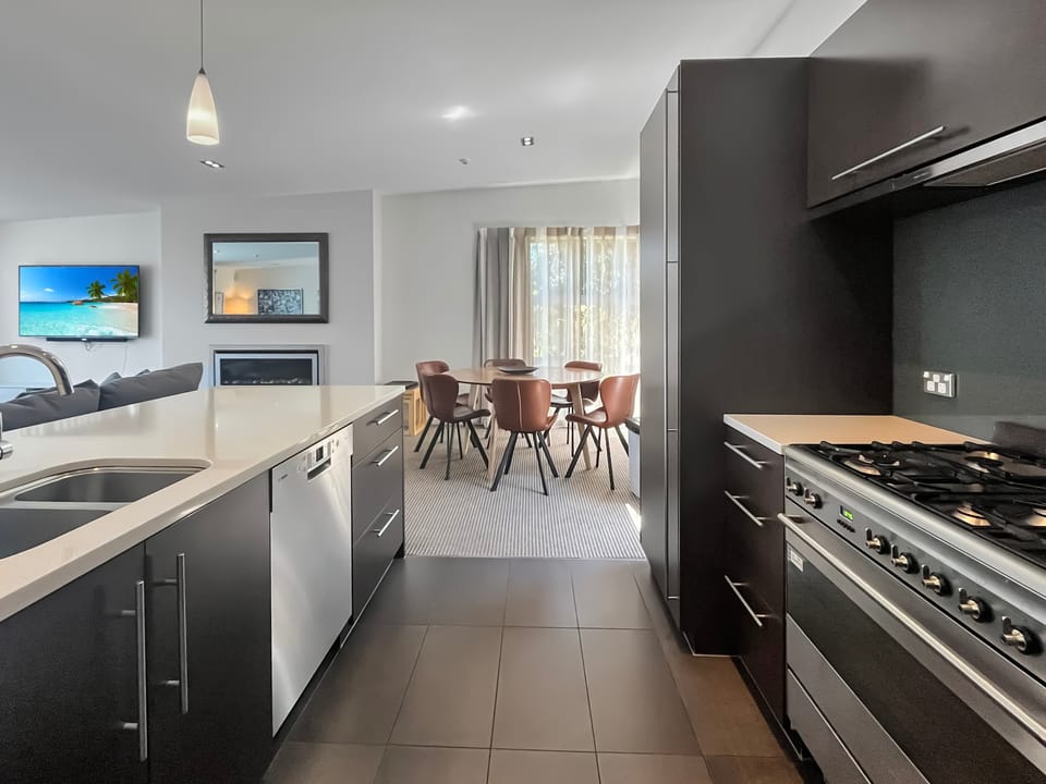 Sleek galley kitchen with modern appliances flowing through to the dining area