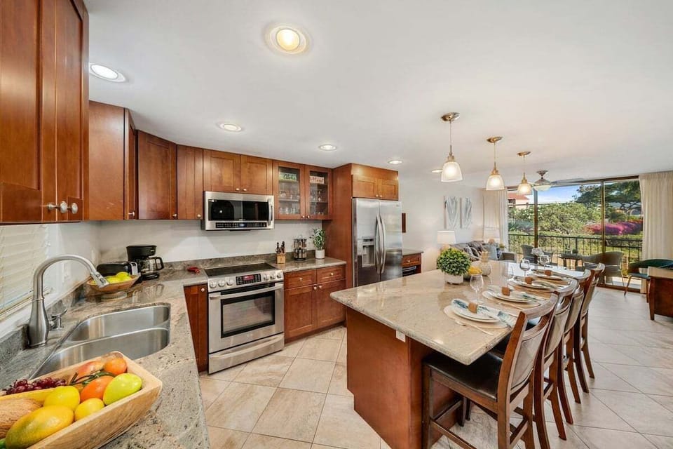 Modern kitchen with large island seating for six, stainless steel appliances, and pendant lighting.