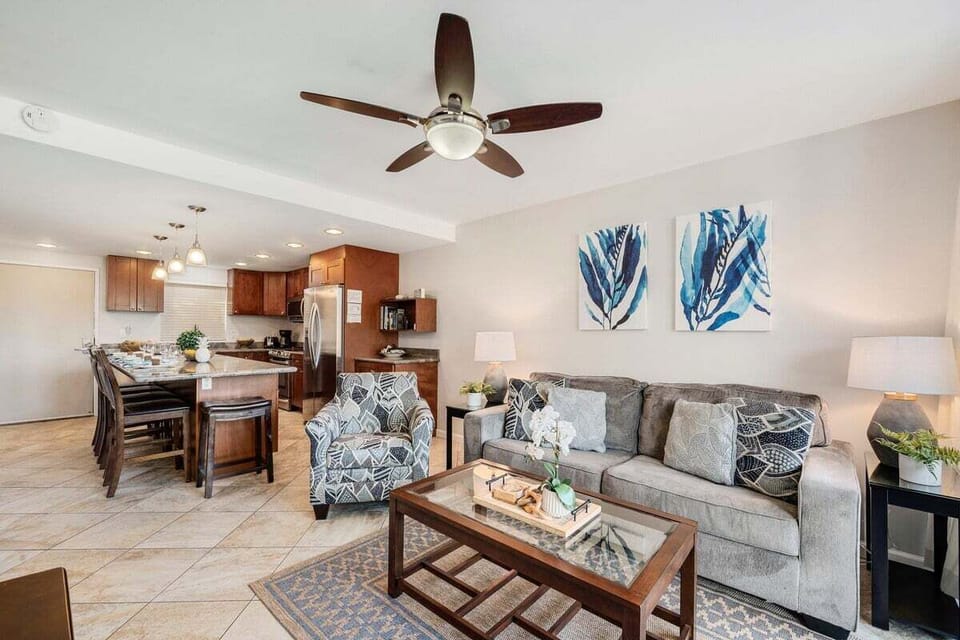 Open‑concept living room and kitchen with modern furnishings and ceiling fan.