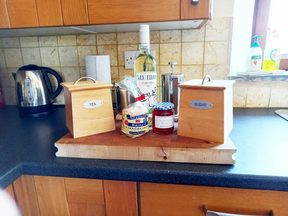 Kitchen detail with chopping board, tea and sugar, wine, jam and welsh cakes