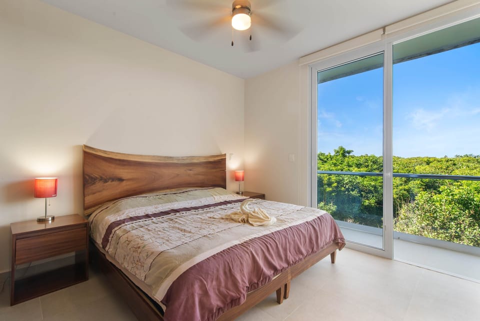 King bed with private balcony and stunning Akumal jungle views.