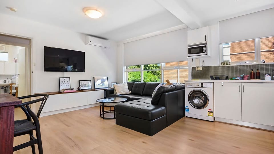 An alternate angle of the living hub highlighting the practical layout that accommodates dining, relaxing, and a smart integrated laundry setup.