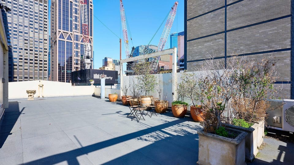 Expansive rooftop terrace with seating and greenery, offering city views