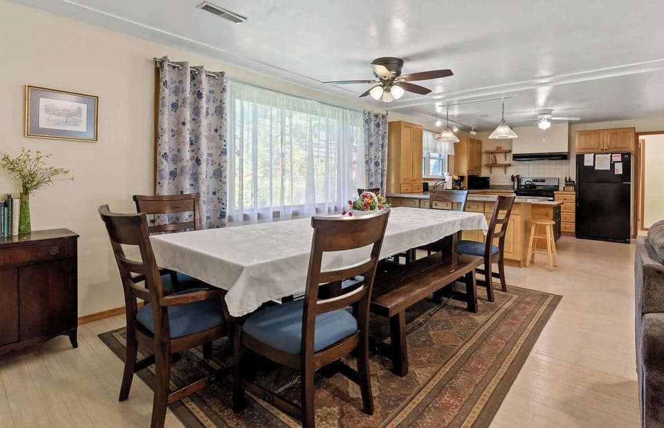 Large 12-piece dining set in the dining area of White Oaks Haven, with a commanding view of the spacious backyard through the huge picture window.
