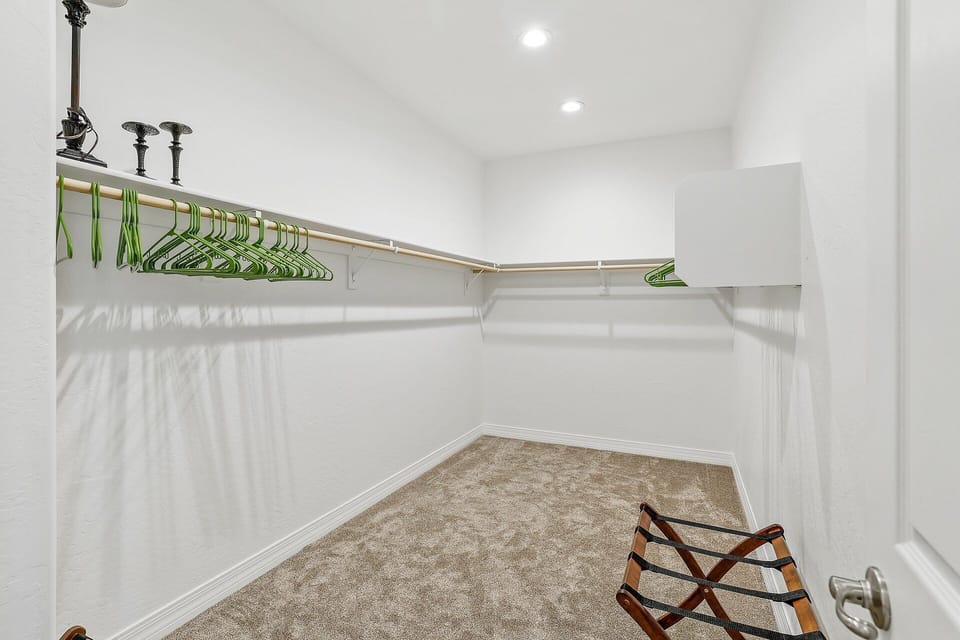 A cozy lounge chair, a flat-screen TV, and a spacious walk-in closet in the master bedroom.