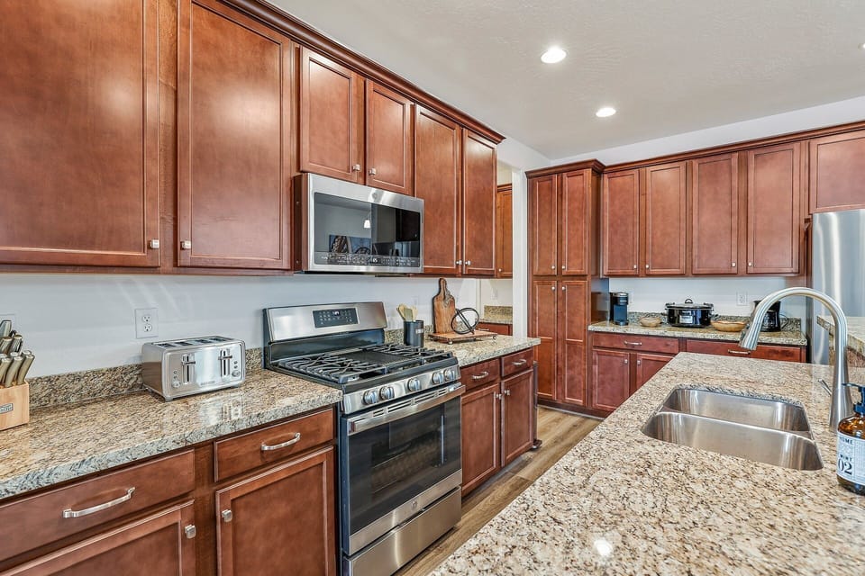 Fully Equipped Kitchen: High-end appliances (refrigerator, stove, microwave, dishwasher), coffee station (Keurig + classic coffee maker), a four-burner stove with a griddle, toaster, and crockpot.