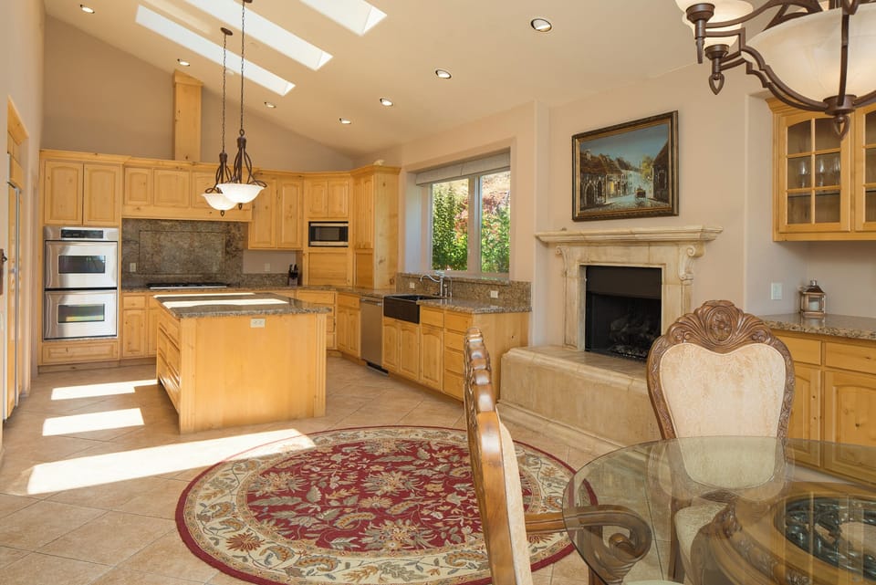 The spacious kitchen is a chef's dream, featuring stainless steel appliances, a large island, and a butcher's sink with a charming view of the flower garden.