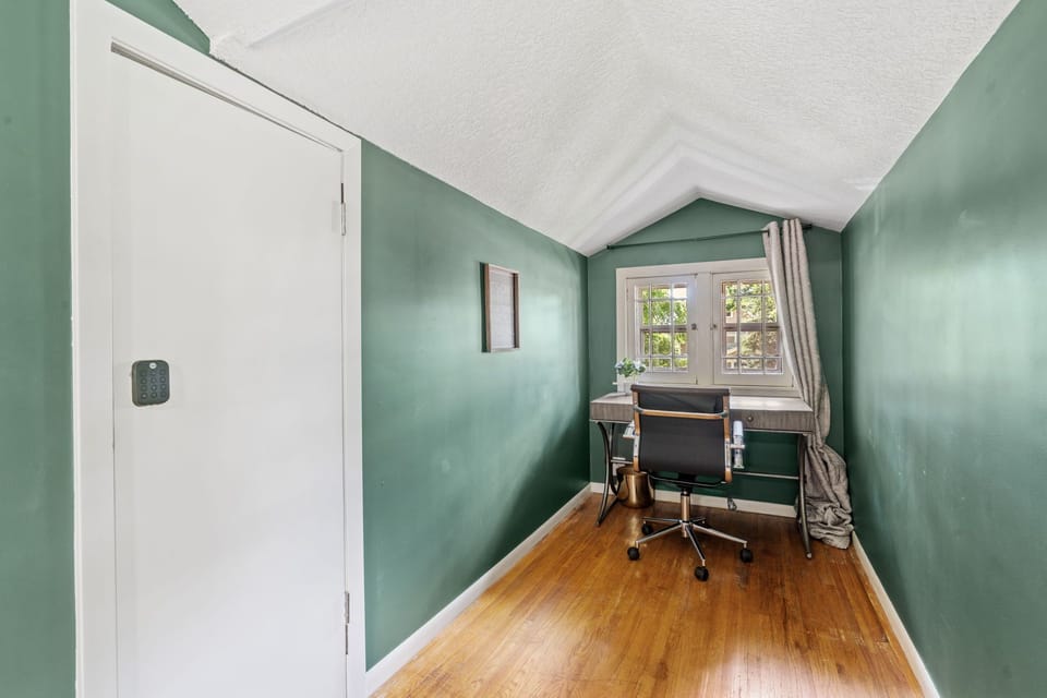 Your private workspace awaits with soothing sage walls, warm hardwood floors, and natural light streaming through charming windows.