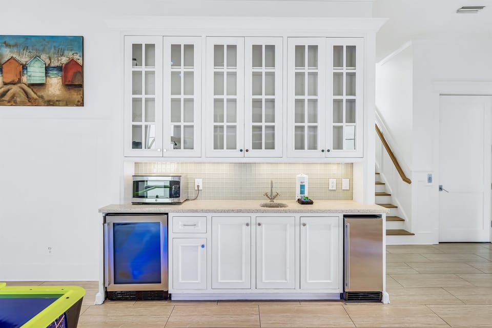1st Floor - Game room with air hockey, custom arcades, 4K Smart TV, dining table, and a wet bar complete with mini fridge, ice maker, sink, and microwave